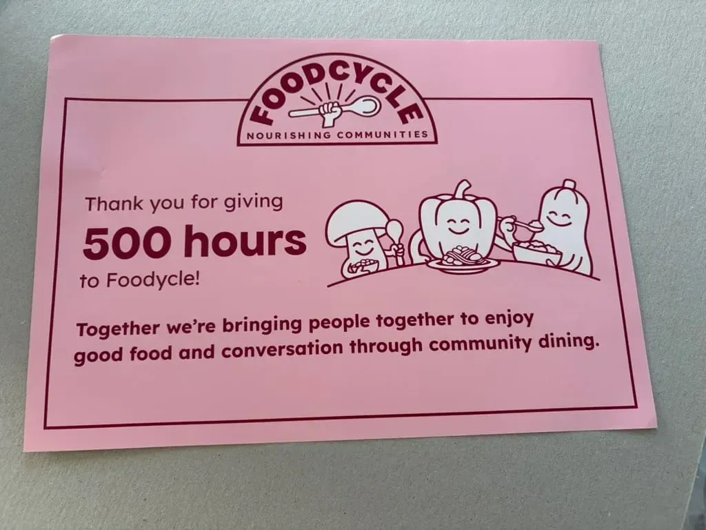 A pink FoodCycle card: thank you for giving 500 hours.